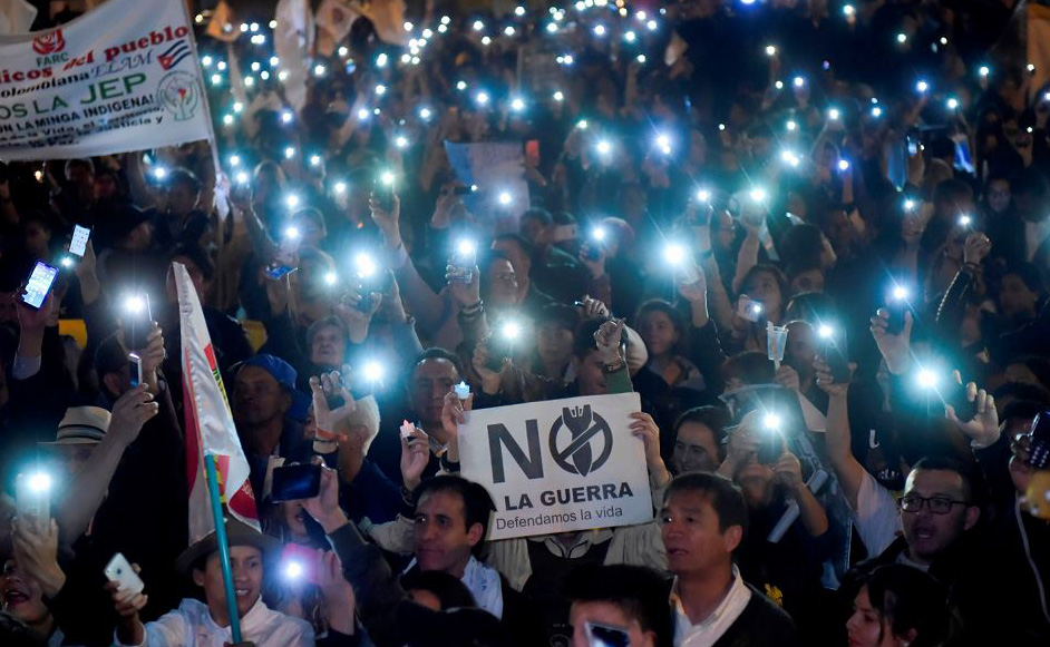 Manifestantes protestam contra a reforma proposta pelo governo de uma Jurisdi&ccedil;]&atilde;o Especial para a Paz (JEP) com uma placa dizendo "n&atilde;o &agrave; guerra" em Bogot&aacute;, Col&ocirc;mbia.